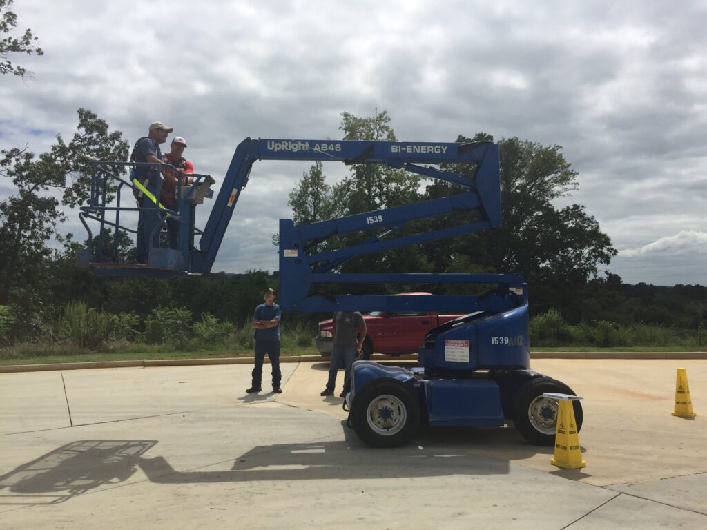 Four men checking a blue construction equipment