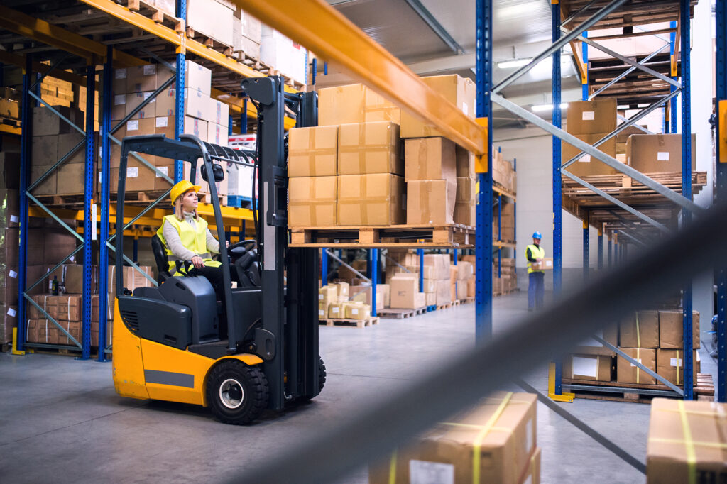 Forklift Operator in Warehouse Lifting Goods on shelf